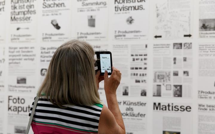 A visitor takes a picture of a wall full of typography posters with her smartphone. 