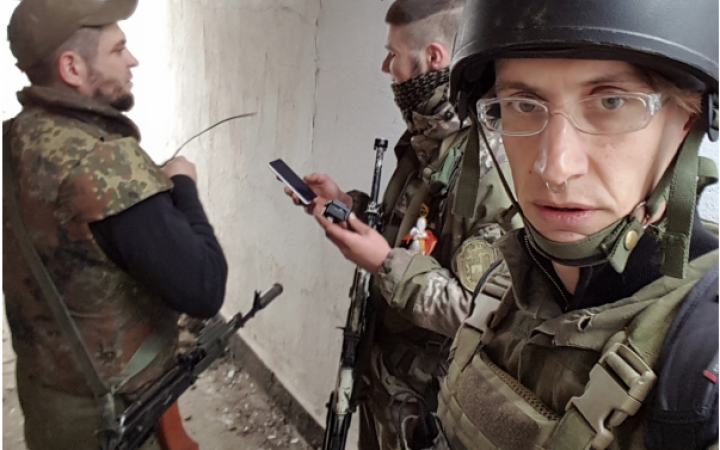 Three persons in military clothing with weapons and mobile phones 