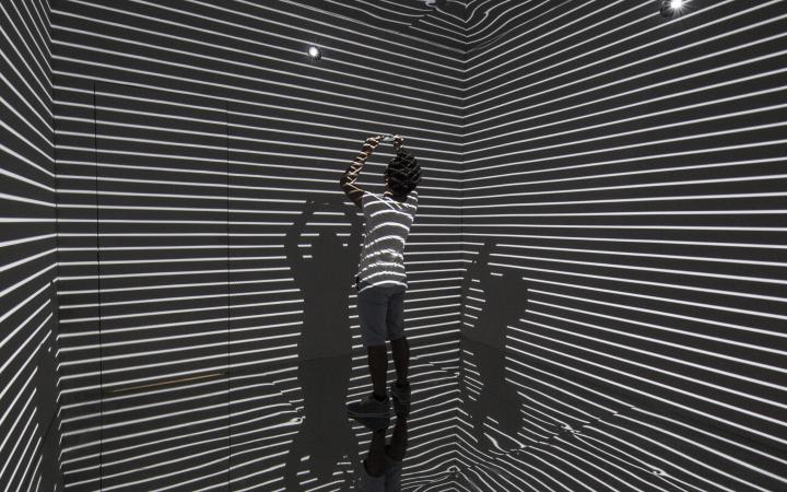 Man in a room which is striated by light.