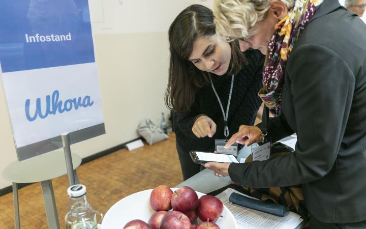 A person can be seen helping a participant with the conference app »Whova« at an event in the context of the forum »Digitale Welten BW«.