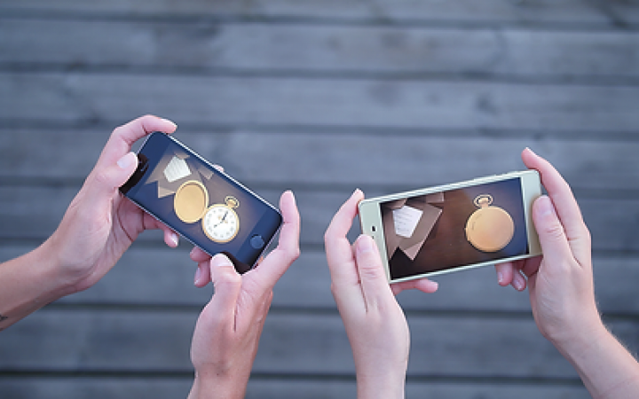 Nahaufnahme von zwei Personen die ihre Smartphone in den Händen halten und gemeinsam »Tick Tock: A Tale for Two« spielen