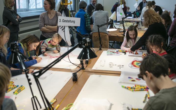 Many children paint at the table during a workshop.