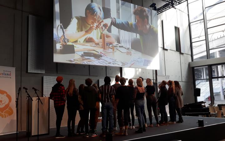A group of students stand under a projection as part of the »Cultural Academy« project at ZKM.