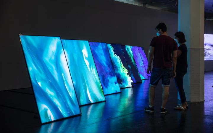 There are seven large flat screens on edge. The screens show aerial photographs of the sea.