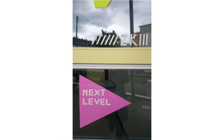 Außenansicht eines Fensters mit Basteleien, dem ZKM-Logo und der Aufschrift »next level«