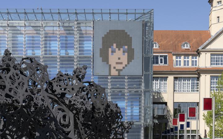 Kryptokunst: Ein illustriertes Gesicht im Pixel-Stil auf der LED Wand des ZKM Kubus.