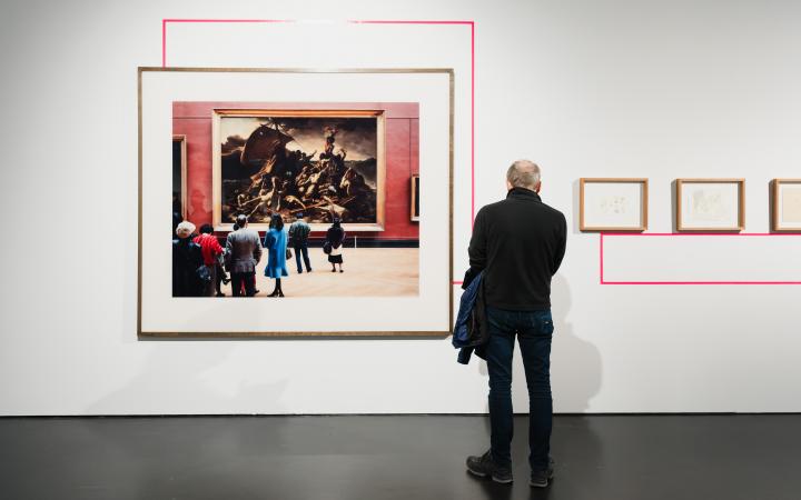 A person stands in front of a painting.