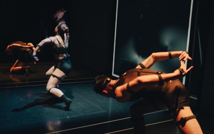 In the photo you can see several (three) dancers moving around the room. The photo has recorded the strong movements. The room in which the dancers are located, is designed completely black and lit only from above with a spotlight. 