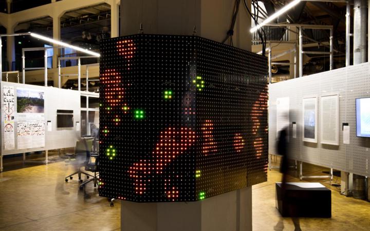 Abbildung des Werkes »Game of Life«, Lichtpunkte auf einem um die Säule verlaufenden Screen