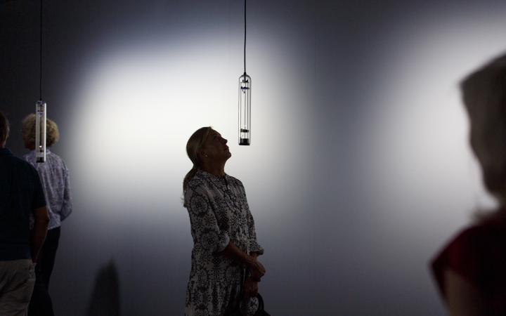 A woman looks up to a sound installation made out of glass.