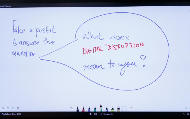 Ein weißes Smartboard mit der Aufschrift: What does digital disruption mean to you?