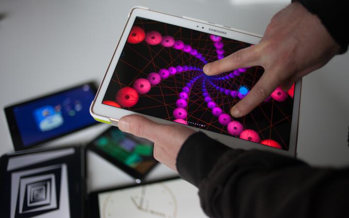 Close-up: Someone is using an artistic app with two fingers. In the background there are other tablets with different artistic apps.