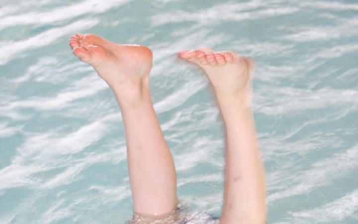 The photo shows two children's feet looking out of the water. 