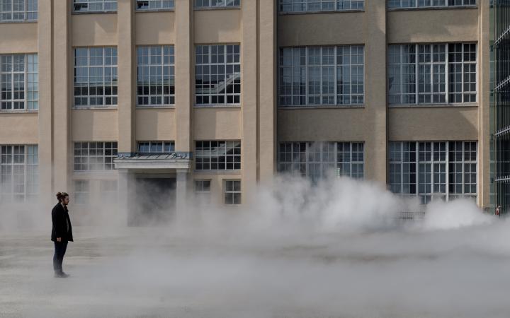 Das Foto zeigt einen Mann ummantelt von der Nebelskulptur der japanischen Künstlerin Fujiko Nakaya. Im Hintergrund ist die Fassade der alten Munitionsfabrik zu sehen.