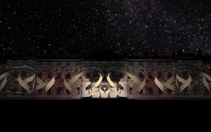 The illuminated Karlsruhe Castle can be seen in front of a sky full of stars. Projected are golden ribbons intertwined with each other