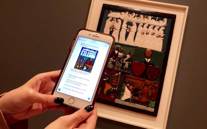 A mobile phone is held in front of a artwork, which then displays more detailed information about the artwork by means of text.