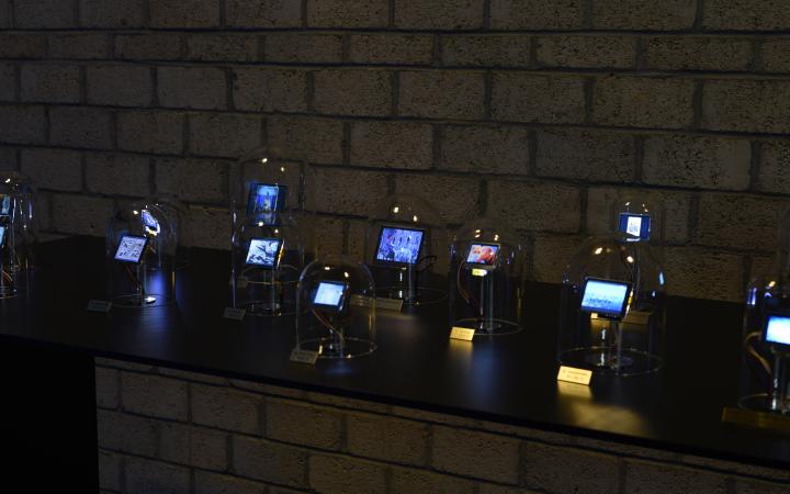 The photo shows a dark table with several glass bells with integrated displays are exposed.