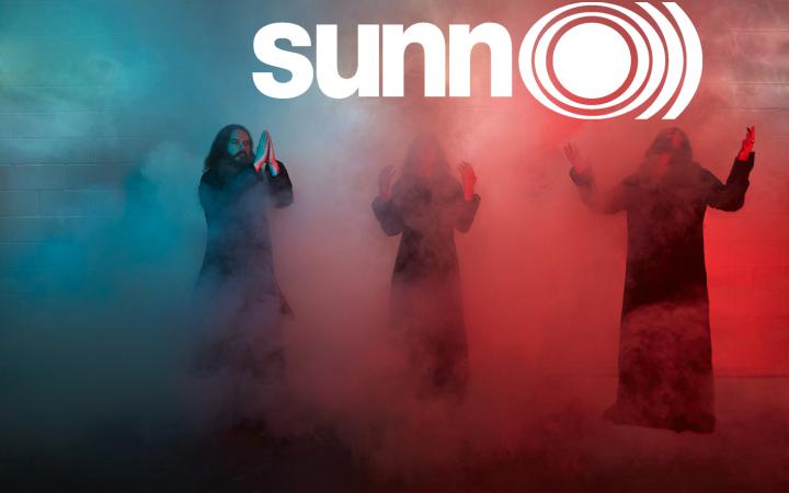 Die drei Musiker der Metalband »Sunn O)))« stehen im blau, weiß und roten Nebel.