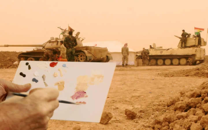 Im Hintergrund sind zwei Panzer und Soldaten zu sehen. Im Vordergrund sind zwei Hände, die ein Papier in der Hand halten, auf dem ein Bild gemalt wird.