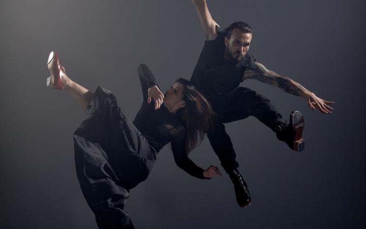 You can see two dancers:inside in black clothes in front of dark gray background