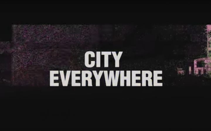Der Schriftzug »City Everywhere« vor einem schwarzen Hintergrund mit Industrie-Gebäude.