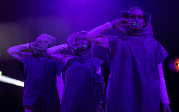 You can see three people, standing next to each other, wrapped in purple light