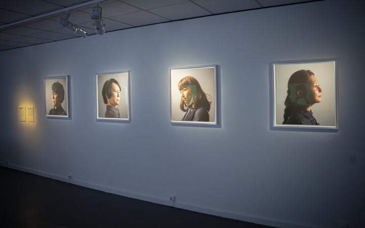 Maija Tammi, »One of Them Is a Human, #1-4«, 2017. Zu sehen sind vier Porträts, die unterschiedliche Menschen abbilden, an einer Wand. 