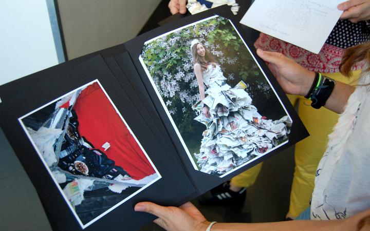 A young schoolgirl presents her framed photographs at a cultural academy event.