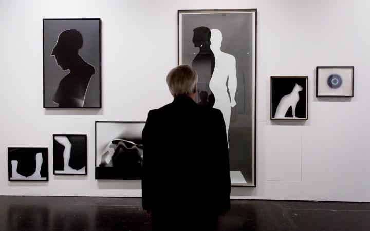 A man is standing in front of different images in black and white