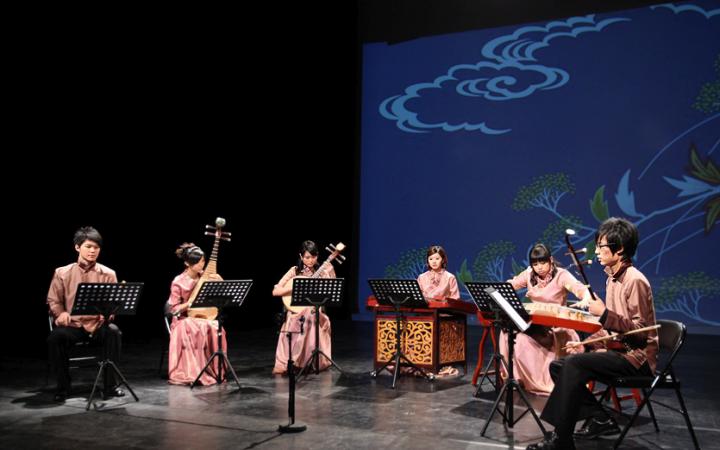 Sechs Musiker in traditioneller chinesischer Kleidung mit ihren Instrumenten auf der Bühne