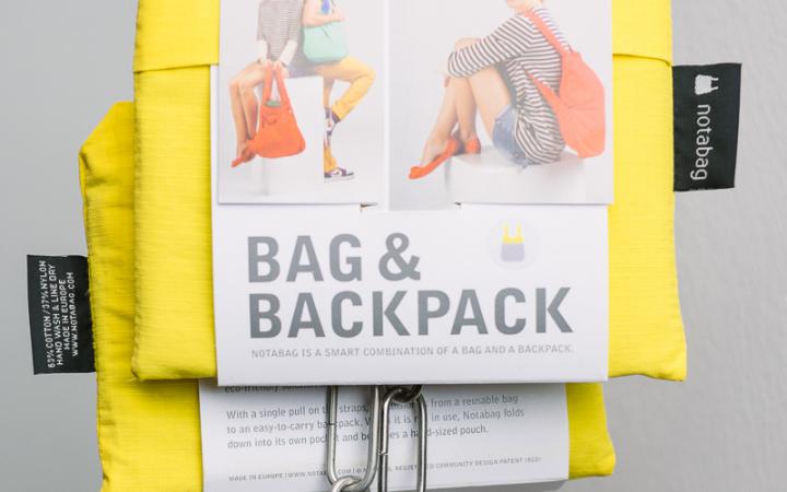 A combination of bag and backpack, folding, yellow, hung up on an iron chain 