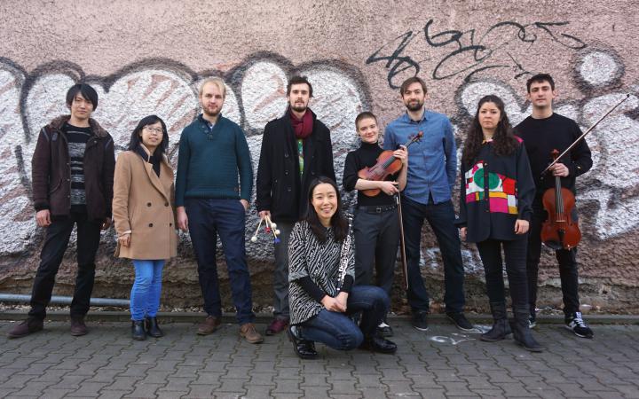 The picture shows the scholarship holders of the International Ensemble Modern Academy (IEMA) in front of a fully sprayed brick wall