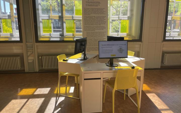 Exhibition view of the object PrEyeCo; three desks with computers and yellow chairs