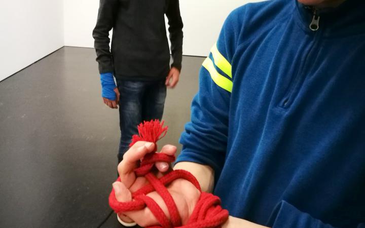 You can see the hands of a pupil gagged with a red rope during the event »Art im Puls«.