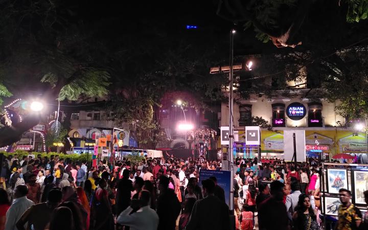 Viele Menschen auf einer Straße bei Nacht versammelt im Rahmen des Kala Ghoda Festivals in Mumbai. 