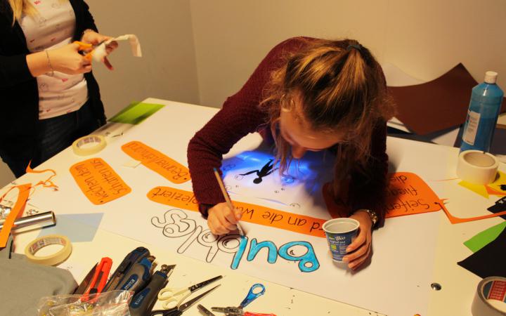 Eine Schülerin gestaltet ein interaktives Plakat