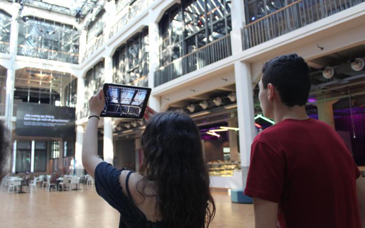 Two students taking a photo of the ceiling of the ZKM with an iPad as part of the event »Global Sound«. 