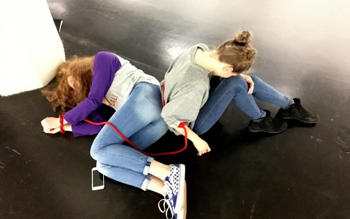 Two schoolgirls lie on the ground with a red rope as part of the »Art im Puls« event.