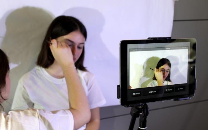 Zu sehen ist ein Mädchen, das vor einer Kamera geschminkt wird im Rahmen einer Veranstaltung der Kulturakademie.