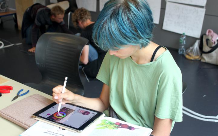A schoolgirl is painting on an iPad as part of a cultural academy event.