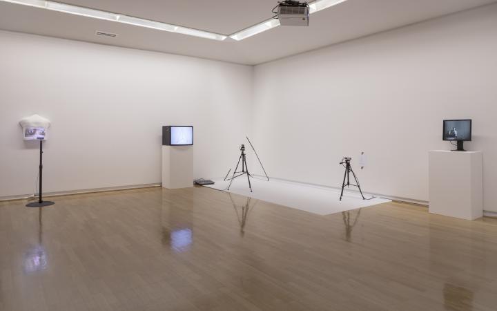You can see the corner of a room with four objects. You can see two screens and two tripods, which are placed in a large distance to each other. 