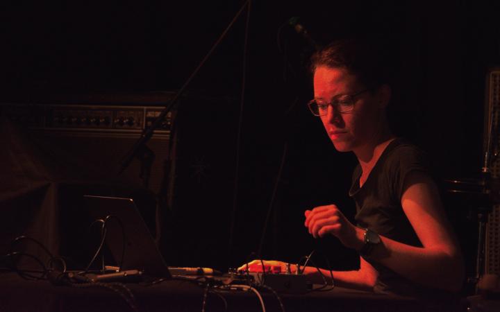 Katharina Schmidt in dark red light at a mixing desk