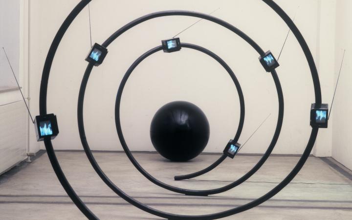 Eine Skulptur aus einer schwarzen Spirale mit kleinen Bildschirmen, die Arbeit heißt »The name« und stammt von Michael Bielicky.