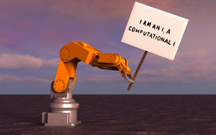 Das Bild zeigt einen Roboter auf einer leeren Kraterlandschaft. Er trägt ein Schild mit der Aufschrift: »I am an I. A computational I.«
