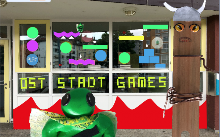 Außenansicht eines Fensters mit Basteleien und der Aufschrift »Oststadt Games«, im Vordergrund weitere Bastelarbeiten