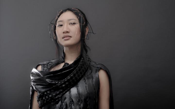 An Asian read young woman in front of a gray background