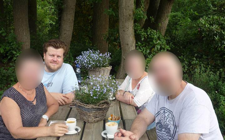 You can see the artist Constant Dullaart in the photo, sitting with three censored people at a wooden table outside.