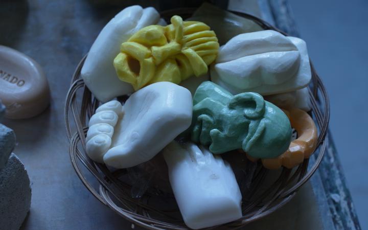 A basket full of soap, carved into different shapes like faces and hands.