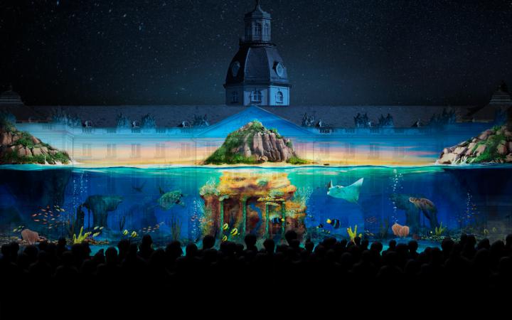 Das Foto zeigt ein Projection Mapping der Gruppe Maxin10sity auf dem Karlsruher Schloss. Zu sehen ist eine mystische Unterwasserwelt. 
