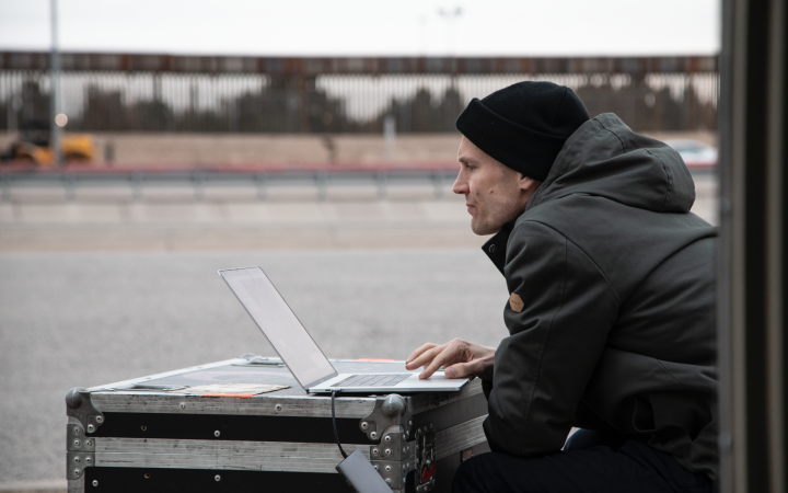 You can see Stephan Schulz sitting in front of a laptop. The laptop is standing on a black case.